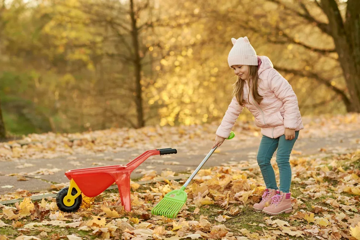 Enfant qui joue dans les feuilles mortes dorées d'un jardin en octobre