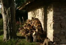Tas de bûches fendues stocké sous un auvent contre un mur de pierre